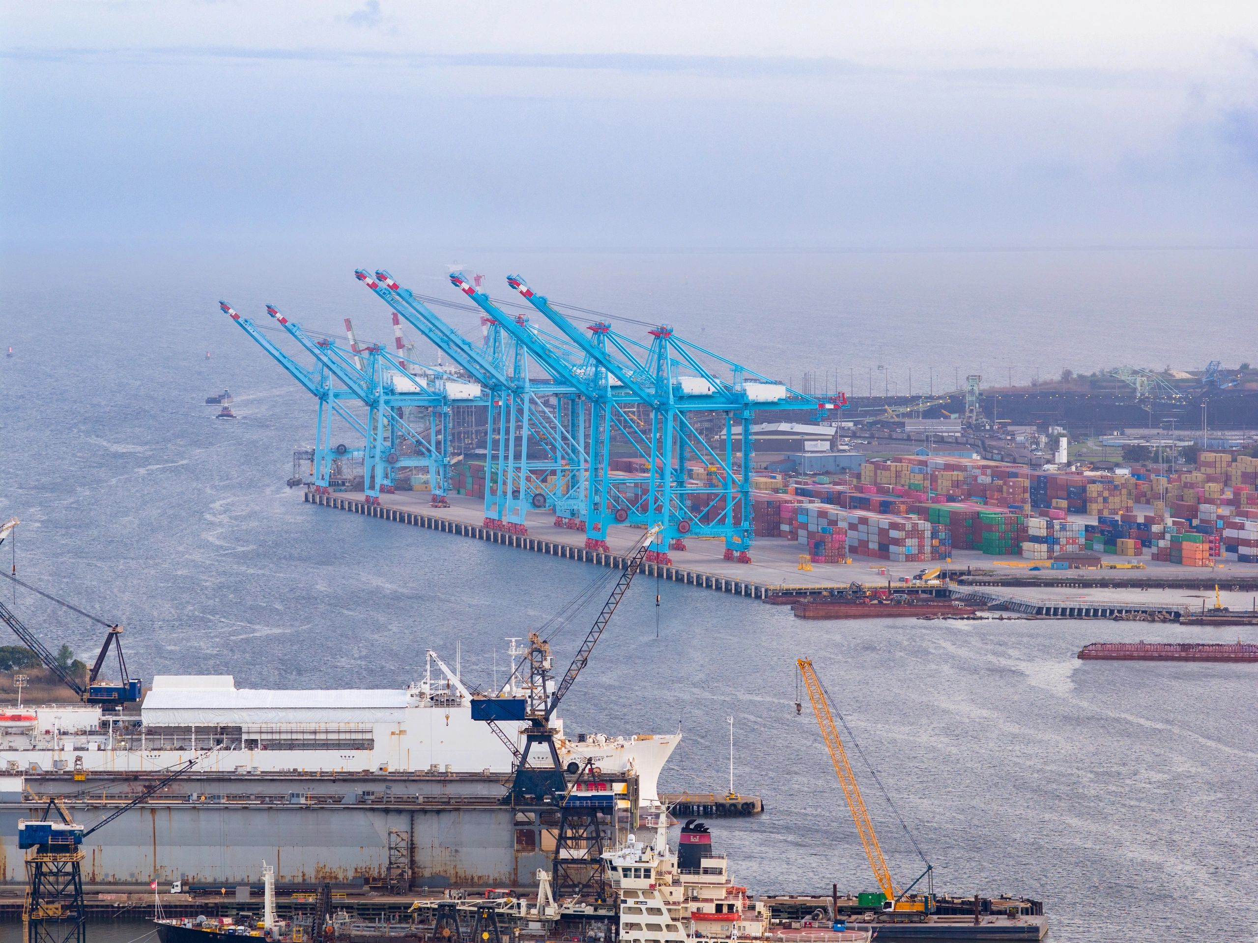 Aerial view of active port operations with cargo vessels and cranes